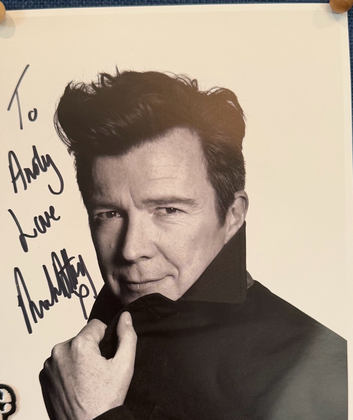 A black-and-white photo of Rick Astley pinned to a board, signed “To Andy, Love Rick Astley”.